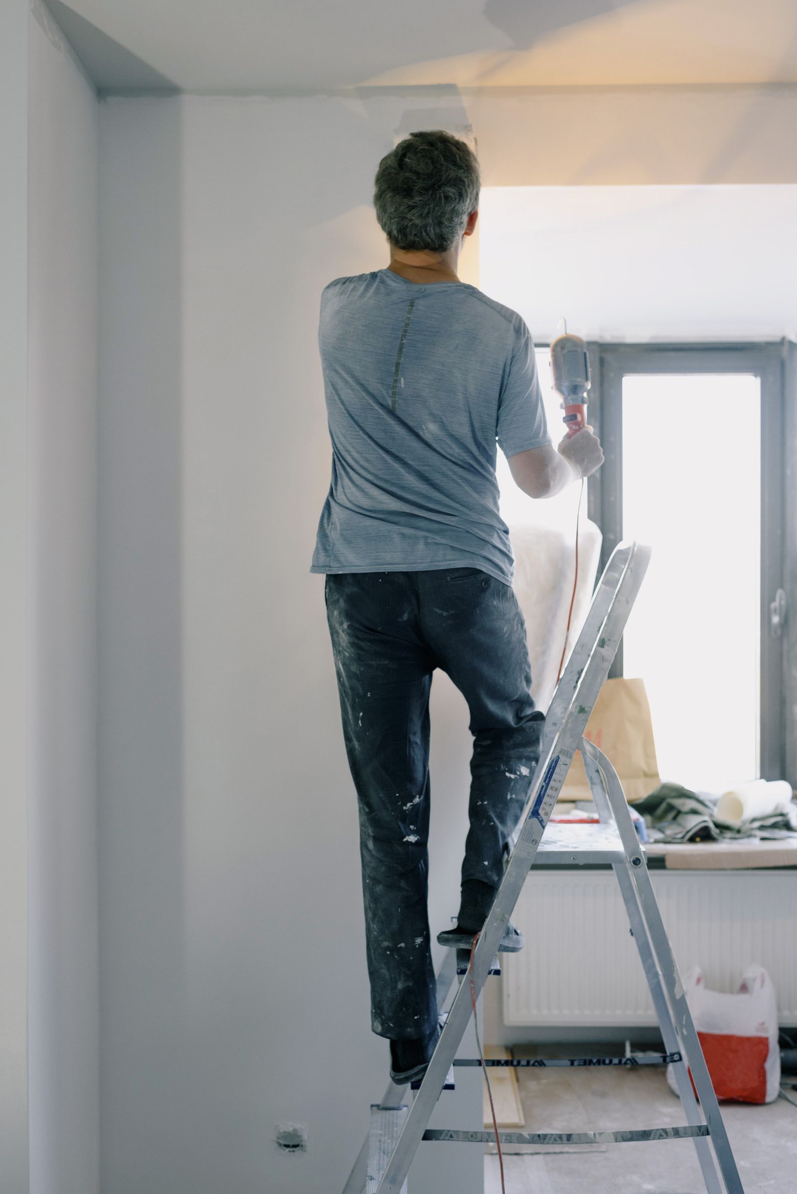 Handwerker bei Reparaturarbeiten auf einer Leiter an der Wand